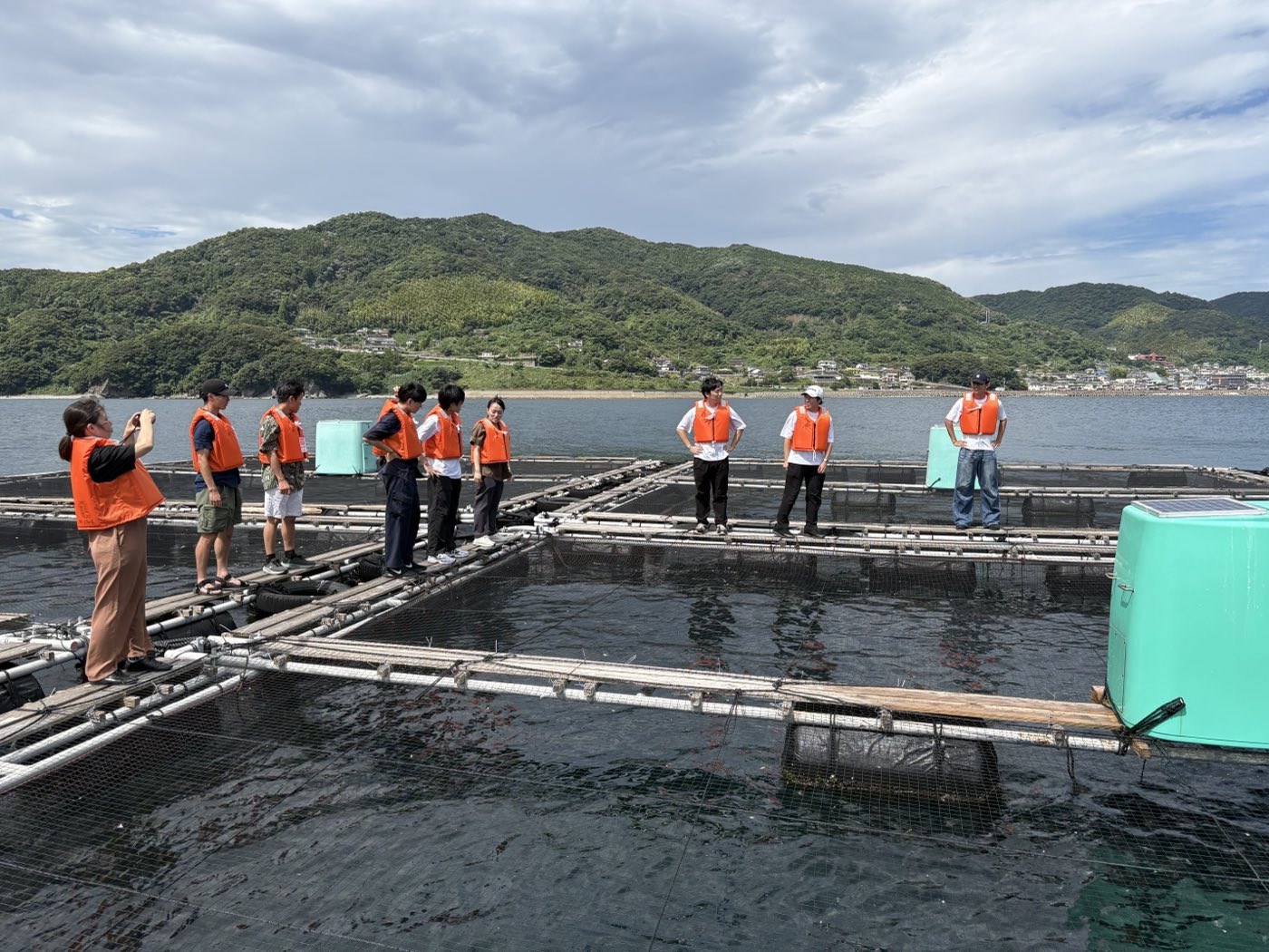 Seminar students on an aquaculture pen listening to the producer